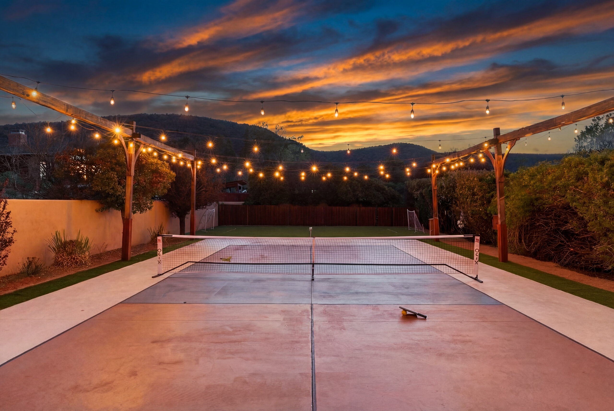 Sedona vacation rental's pickleball court with string lights lit at night.