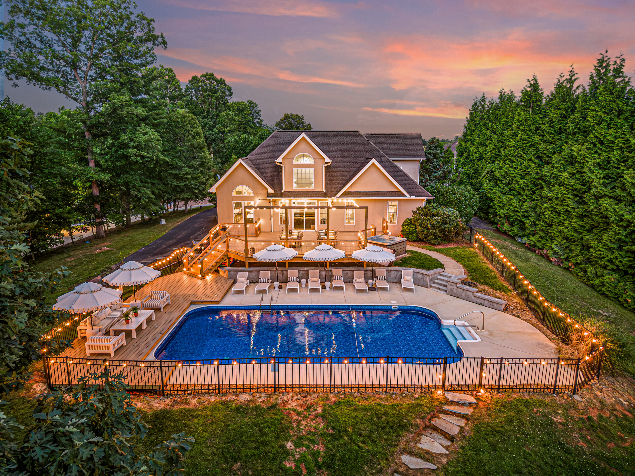Twilight Photo of the Backyard of an Asheville Luxury Home with swimming pool illuminated by outdoor stringlights.