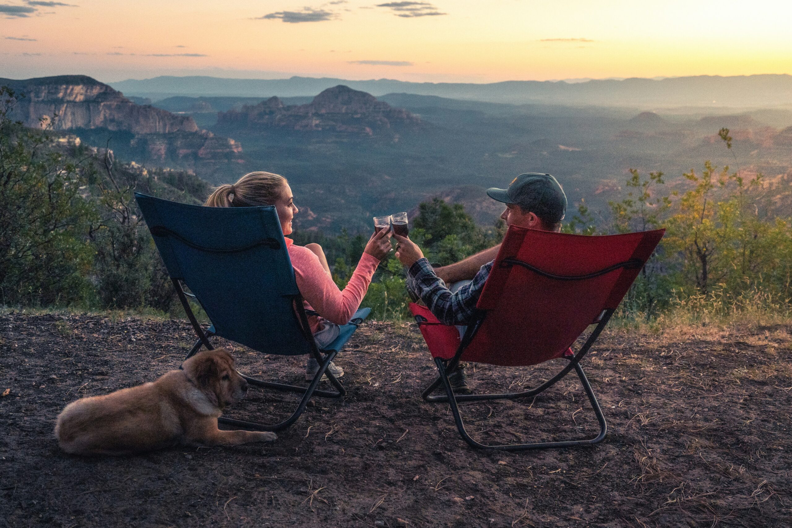 A couple toasting with a glass of wine while camping on Sedona's mountains.