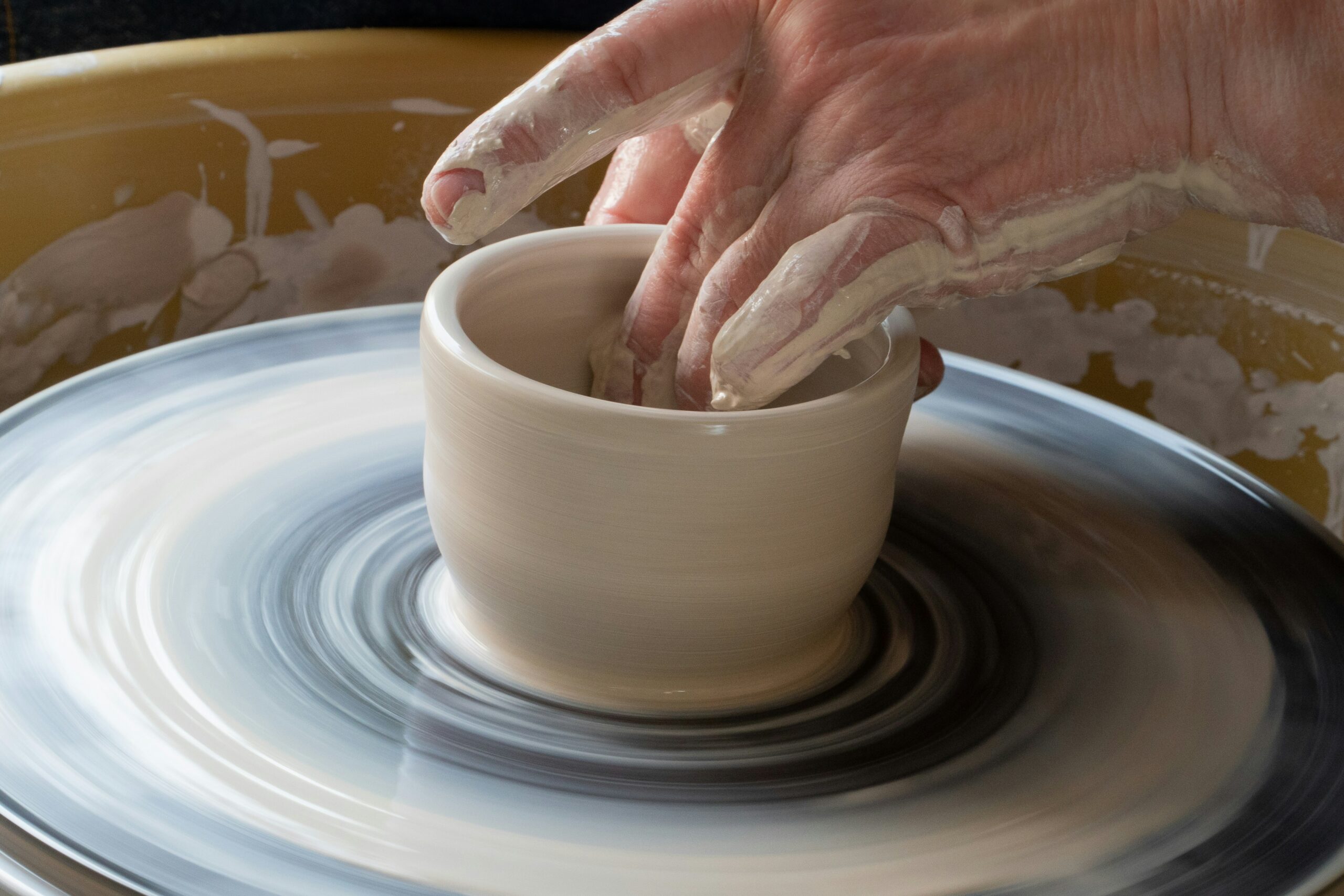 Close-up of hands shaping wet clay on a pottery wheel during an Asheville arts and crafts workshop
