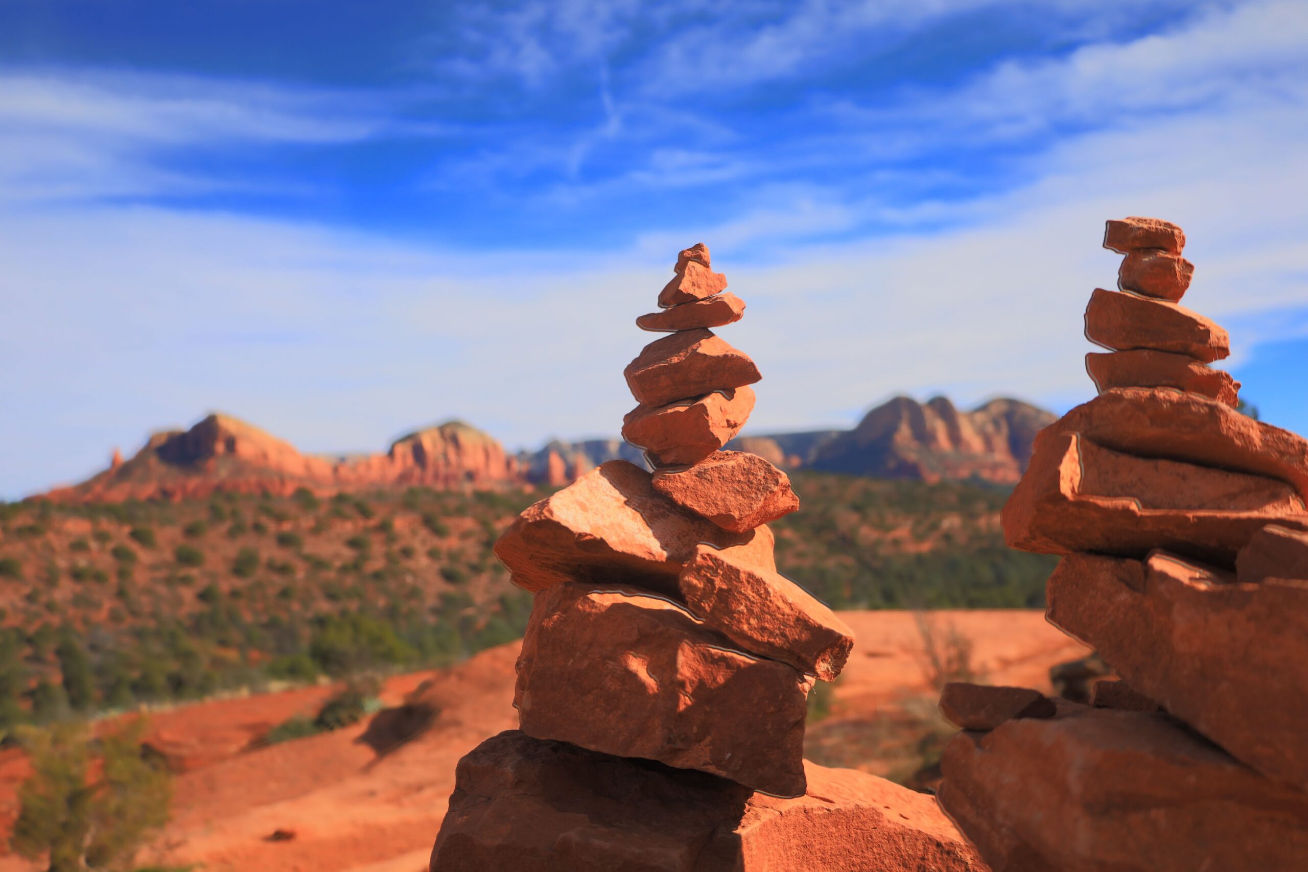 Stacked red rock cairns along a Sedona vortex trail overlooking the desert landscape