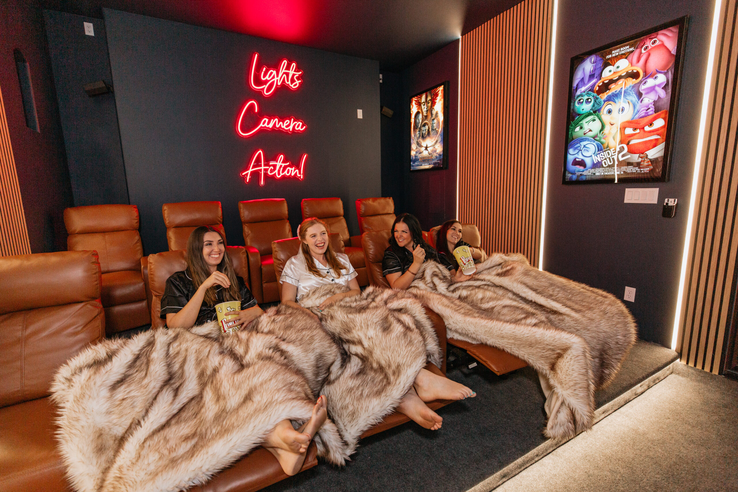 Group of women in pajamas watching a movie in the private home theater of a Sedona vacation rental during a girls' trip.